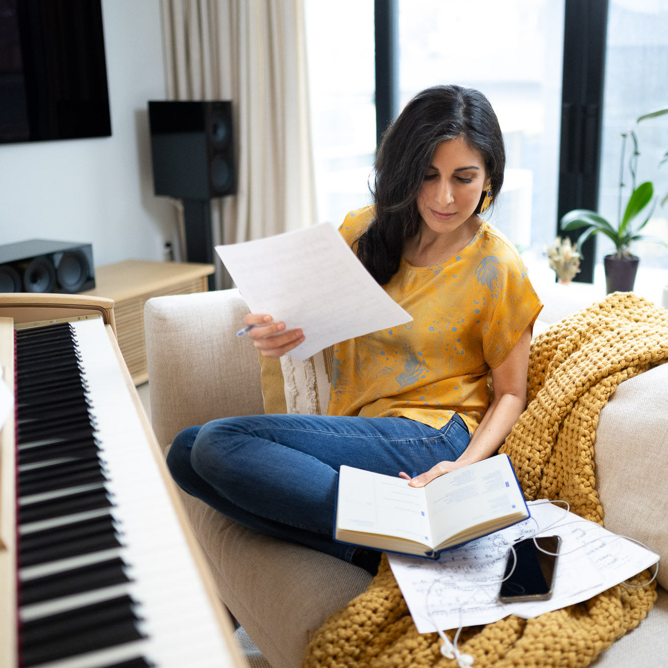Pianist reflecting on her practice using the Muse and Mate practice journal for musicians by the piano and checking music scores.