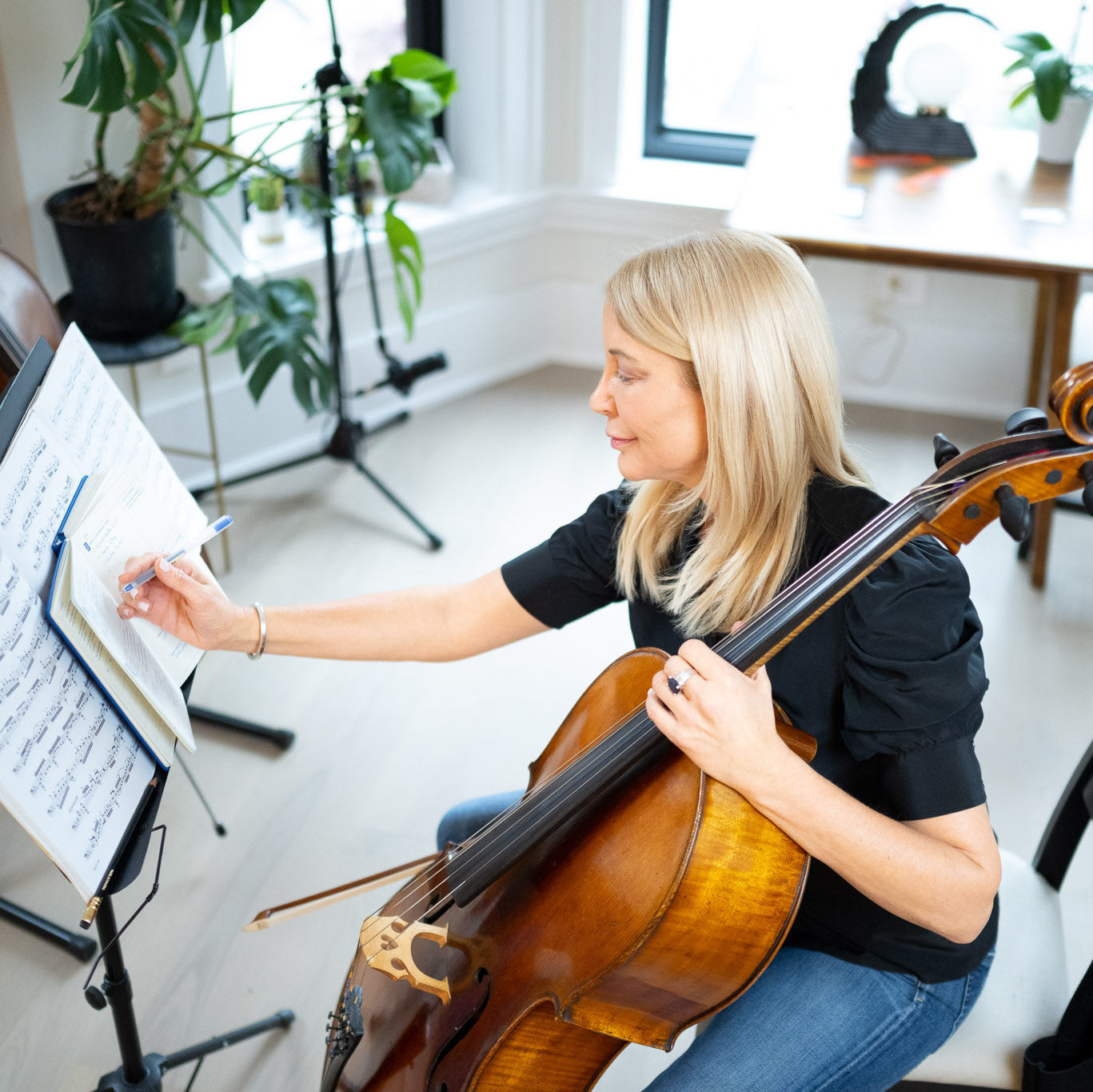 Cellist writing on her Muse and Mate practice journal for musicians while practicing the cello.